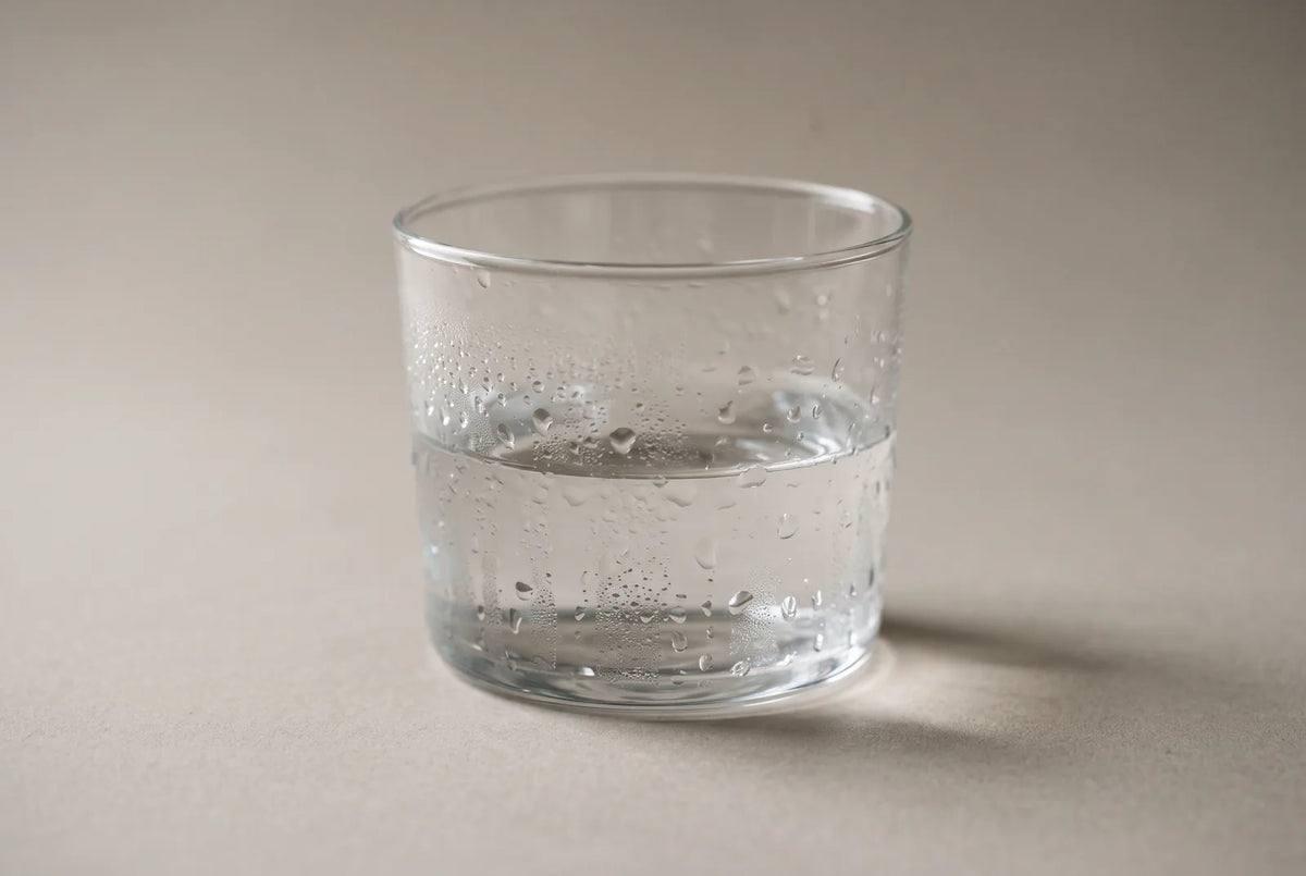 Verre d'eau posé sur une table de chevet, à côté d'un humidificateur d'air, dans une chambre claire.