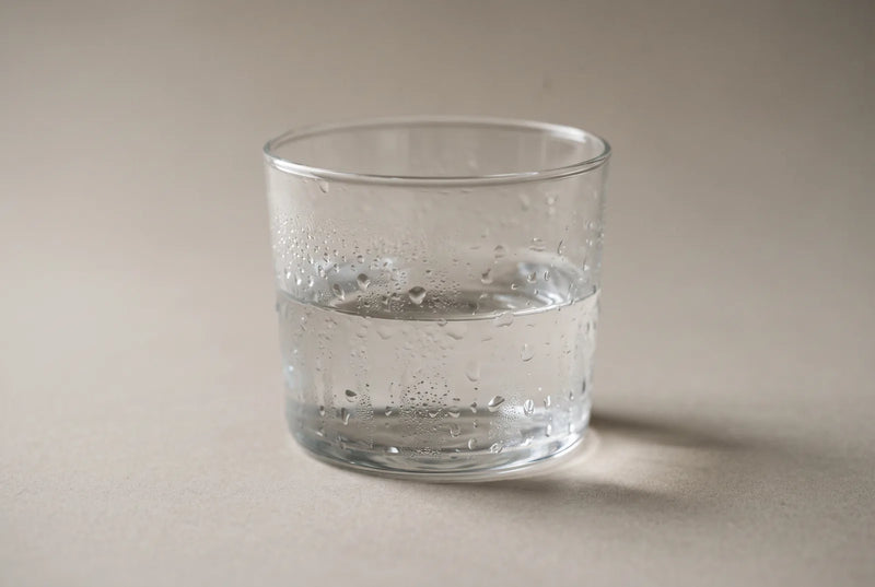 Verre d'eau posé sur une table de chevet, à côté d'un humidificateur d'air, dans une chambre claire.